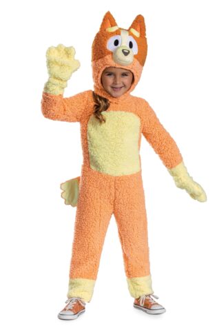 Child in an orange and cream fluffy fox costume, hood up, waving with one hand.